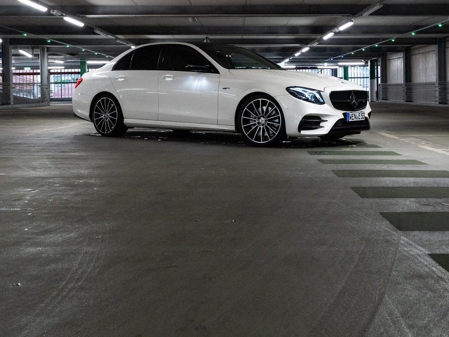 Mercedes-AMG E53 Limousine in Weiß, ganzes Auto aus der Distanz in der Tiefgarage