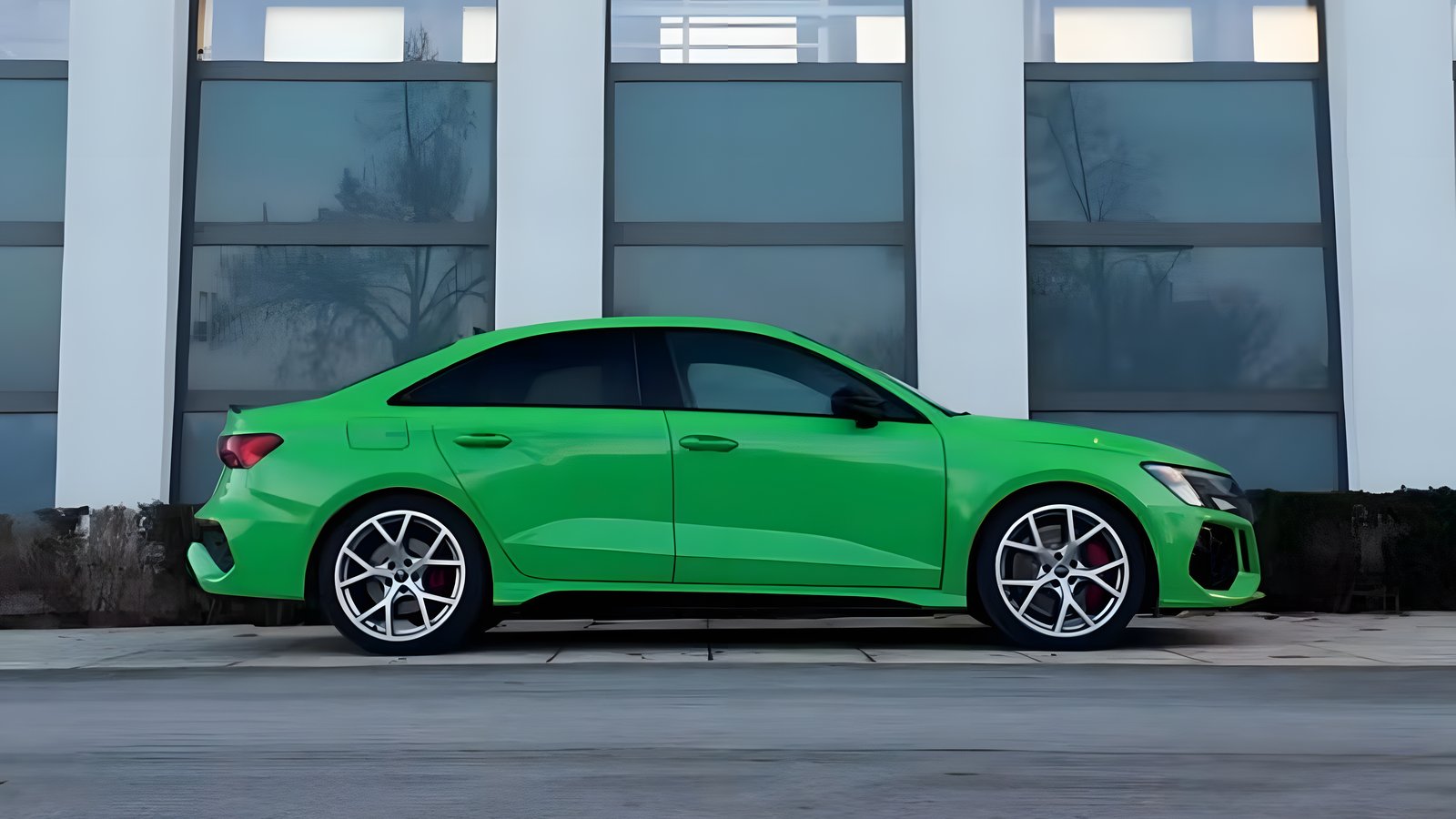 Kyalami green Audi RS3 sedan, side view in front of a glass facade