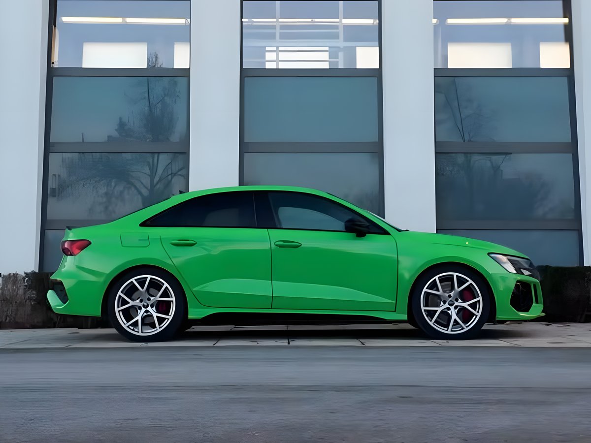 Audi RS3 Limousine in Kyalami-Grün, Seitenansicht vor einer Glasfassade